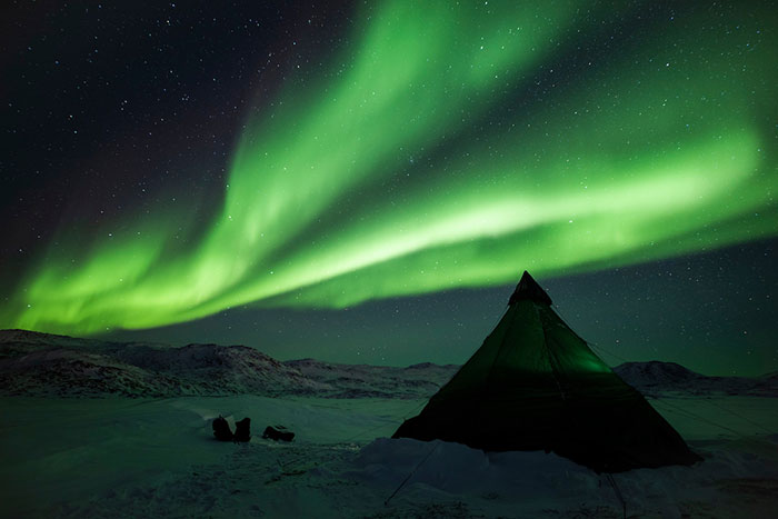 Immagine spettacolare dell'aurora boreale in Groenlandia osservata di notte da campo tendato