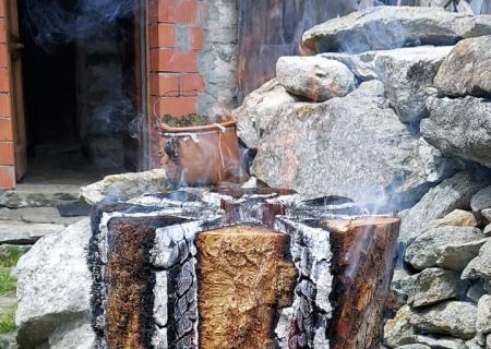 esperienze personalizzate in baita piemontese con famiglia fattore preparando un falo con ceppo di legno a Piedicavallo
