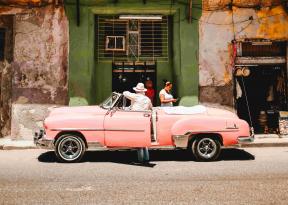 foto con auto d'epoca rosa ed edificio cubano durante tappa a la havana itinerario su misura pianificato da Tour Operator specializzato